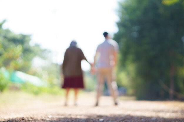 Linse verwischte hintere Ansicht von den jungen asiatischen Paarhändchenhalten