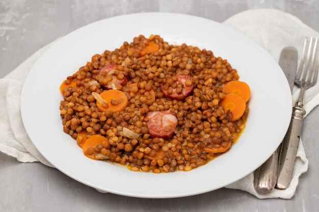 Linsen mit Chorizo und Karotten auf weißem Teller. Typisches spanisches Rezept