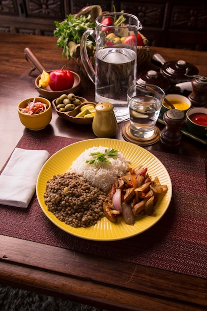 Linsen sautiertes Hähnchenreis peruanisches traditionelles Essen Mise en Place Holztisch