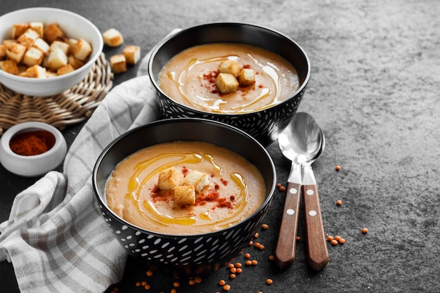 Linsencremesuppe mit Paprika und Croutons in schwarzen Keramikschalen