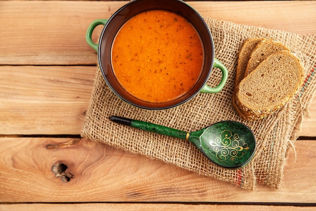 Linsensuppe in einem Suppenteller auf einem Segeltuch auf einem hölzernen Hintergrund. Ansicht von oben