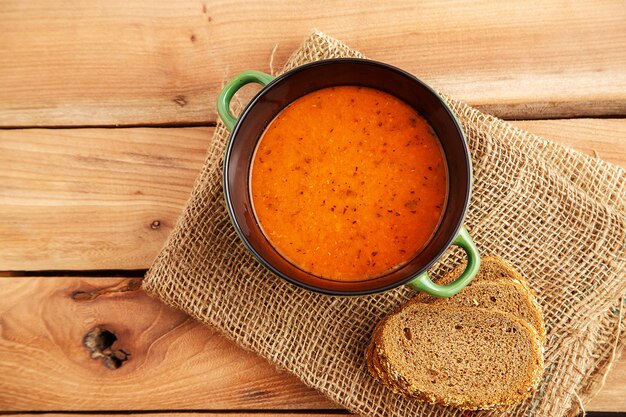 Linsensuppe in einem Suppenteller auf einem Segeltuch auf einem hölzernen Hintergrund. Ansicht von oben