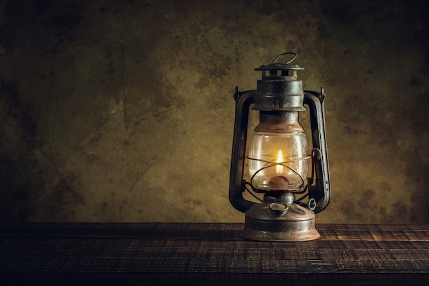 Foto linterna de aceite de la lámpara de queroseno que se quema con luz tenue resplandor en piso de madera envejecida