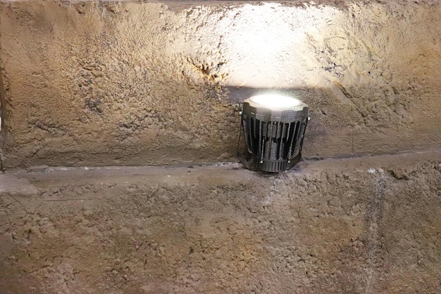 Una linterna brilla en la pared de una casa en primer plano de una pared de piedra