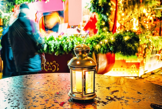 Linterna brillante con la vela dentro de ella de pie sobre una de las mesas en el mercado navideño en invierno Riga en Letonia.