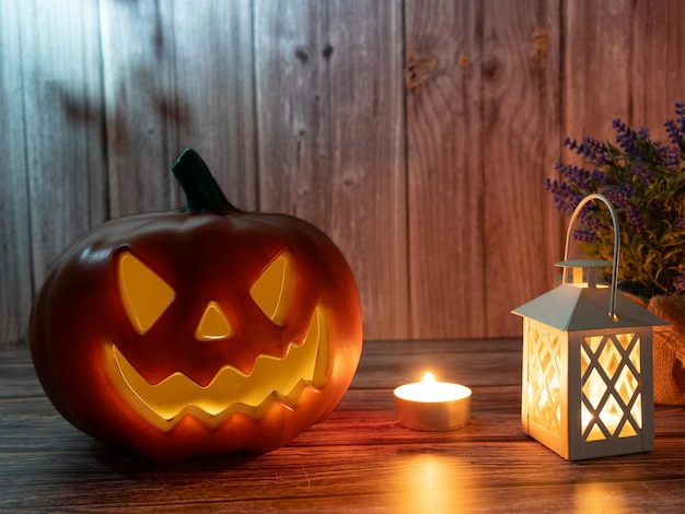 Linterna de cabeza de calabaza de Halloween con velas y una calabaza sobre fondo de madera