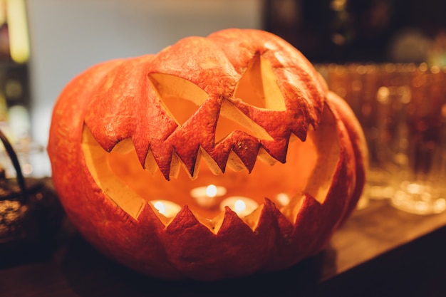 Linterna de calabaza de Halloween con hojas secas con fondo negro.