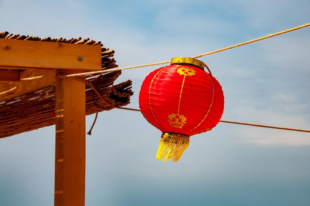 Foto linterna china roja con flecos dorados en el fondo del cielo azul de verano