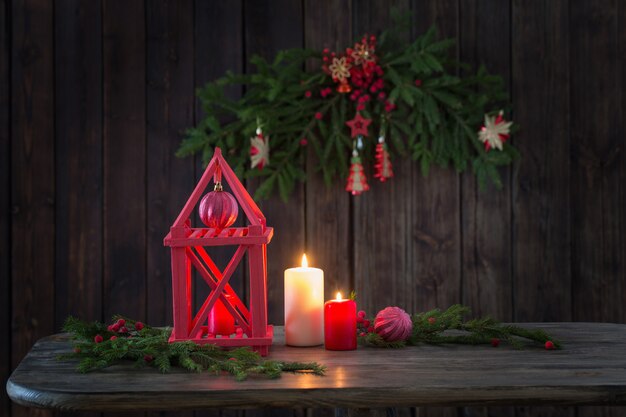 Linterna de madera con velas y ramas de Navidad en madera