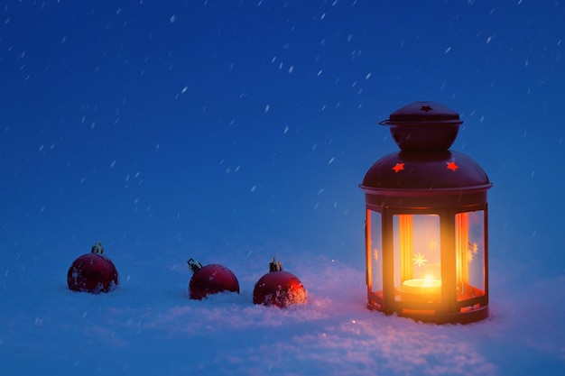 Foto linterna para navidad en la nieve con juguetes navideños. nochebuena