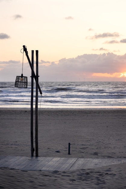 Linterna con parabrisas de mimbre en un doble poste de madera y barra transversal en la orilla del mar