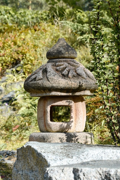 Linterna de piedra asiática tradicional en el jardín verde de verano