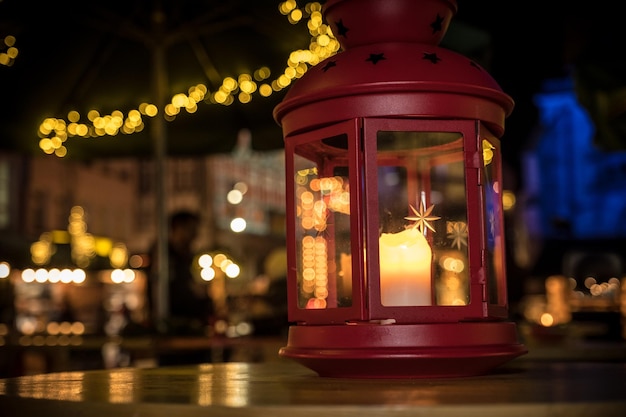 Linterna roja con vela en una mesa en el mercado de Navidad