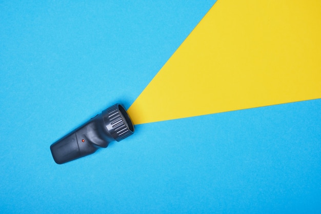 Linterna sobre un fondo azul con un rayo de luz amarillo, hecha de espacio de copia en papel. vista superior