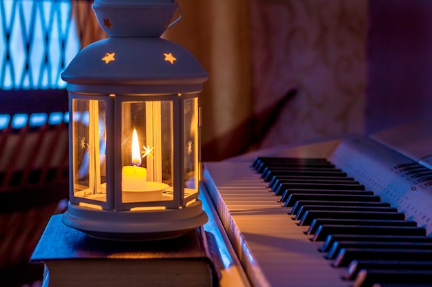 Linterna con una vela cerca de un piano durante un concierto nocturno