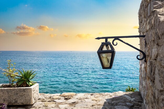 Linterna vieja en la pared cerca del mar al atardecer