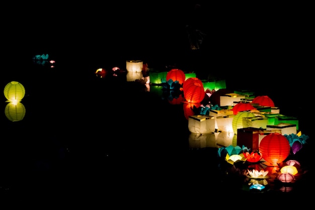 Linternas de papel flotante de colores en el agua oscura