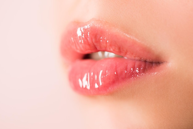 Lippenpflege für natürliche Schönheit. Weibliche Lippen mit rosa Lippenstift. Der offene Mund der sinnlichen Zärtlichkeit der Frauen. Rote Lippe mit glänzendem Lipgloss. Nahaufnahme, Makro mit schönen Mündern. Sinnliche Lippen einer jungen Frau.