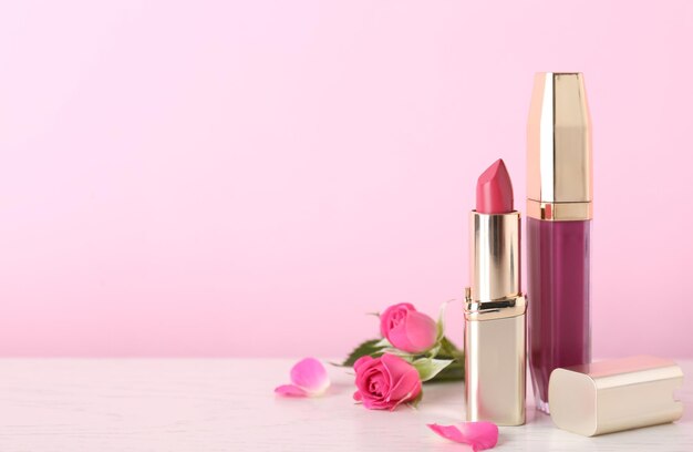 Lippenstift und Lipgloss mit Blumen auf Tischfläche für Text