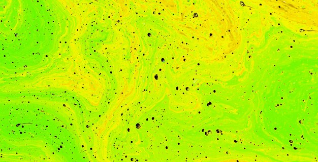 Un líquido verde y amarillo con puntos negros en la superficie.