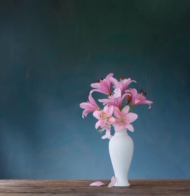 Lírio rosa em vaso branco sobre fundo azul