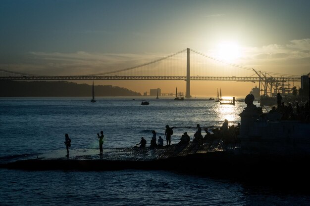 LISBOA Portugal 27 de octubre de 2017 personas viendo la puesta de sol con vistas al puente 25 de Abril sobre el río Tajo cerca de Praca Do Comercio en Lisboa Portugal