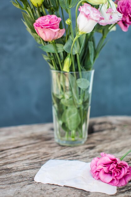 Lisianthus-Blumenstrauß auf einem Holztisch mit leerer Notiz