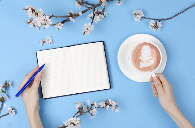 Lista de desejos para planos futuros. composição plana leiga com flores, bloco de notas e café