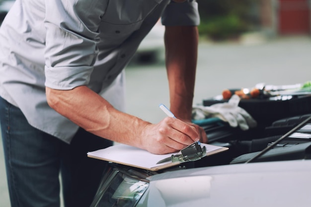 Lista de verificación de trabajo de escritura mecánica en el portapapeles en un taller con un automóvil