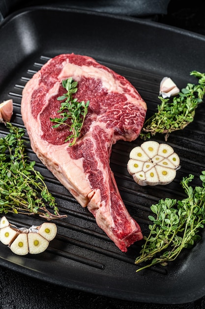 Listo para cocinar Vaquero crudo o filete de costilla en una sartén a la parrilla Fondo negro Vista superior