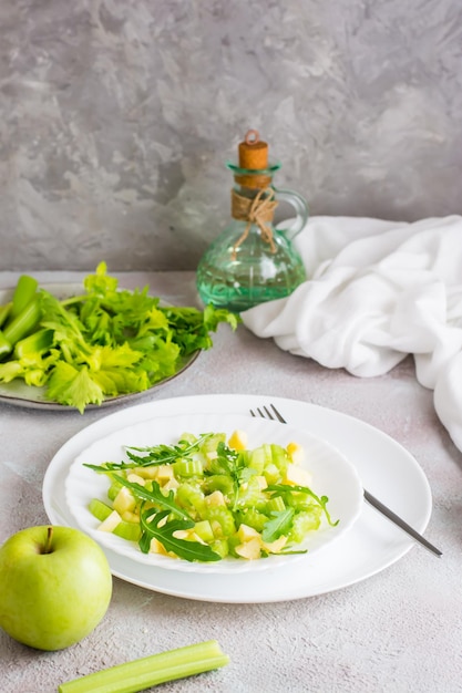 Listo para comer ensalada fresca de apio, manzana verde, rúcula y semillas de sésamo en platos sobre la mesa. Dieta vegetariana. Vista vertical