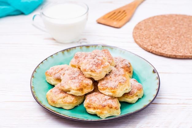 Listo para comer galletas de requesón en un plato sobre una mesa de madera.