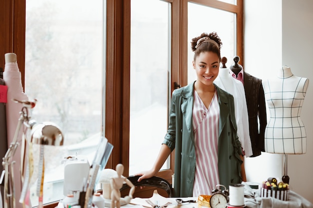 Listo para crear un nuevo estilo elegante mujer africana de pie en el estudio de diseño