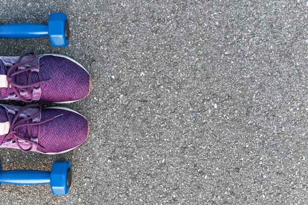 Listo para entrenar. Foto recortada de volquetes y zapatillas de color púrpura en el fondo de asfalto. Motivación deportiva