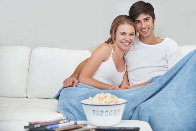 Listo para entretenerse Una pareja joven viendo una película en casa