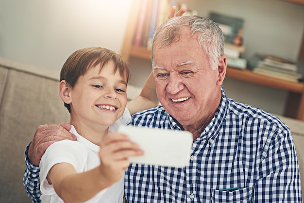 Foto ¿estás listo? gramps shot de un abuelo feliz y su nieto tomándose un selfie juntos en un teléfono móvil en casa