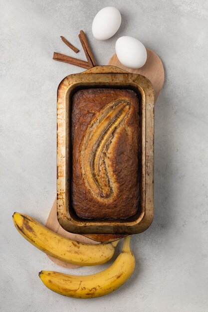 Foto listo pan de plátano fresco en una fuente para hornear rectangular con ingredientes sobre un fondo claro