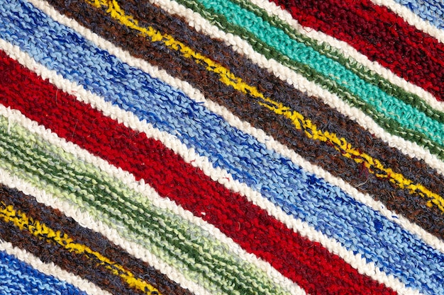 Listras coloridas diferentes na superfície do tecido de malha. close-up de tapetes retrô de têxteis ou tapetes. a textura do tecido é uma combinação com a geometria das linhas. produto artesanal