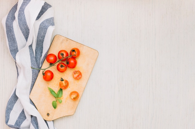 Listras padrão toalha e tomate cereja na tábua sobre a superfície de madeira