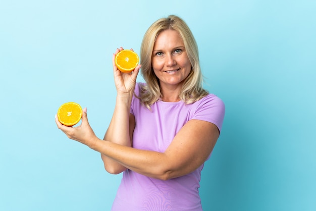 Litauische Frau des Mittelalters lokalisiert auf blauer Wand, die eine Orange hält