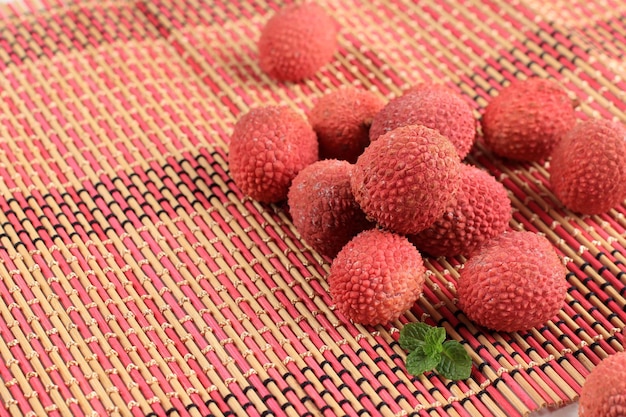 Litchi, lichee, lychee ou lichi, fruta fresca de lychess em fundo de bambu rosa