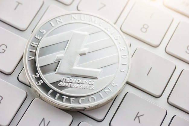 Foto litecoin-münze auf einer weißen tastatur digitale kryptowährung, copyspace für ihren individuellen text. ideal für webseiten und zeitschriftenlayouts