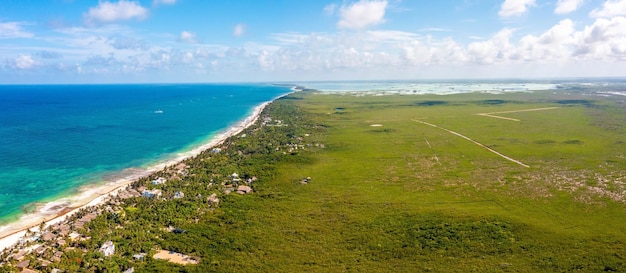 Litoral aéreo de Tulum junto à praia com um mar mágico do Caribe e pequenas cabanas à beira-mar. Bela natureza de Tulum. Vista aérea do México.