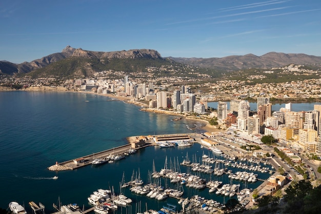 Litoral da estância mediterrânea de calpe, espanha, com arranha-céus de lago e mar e iates ...