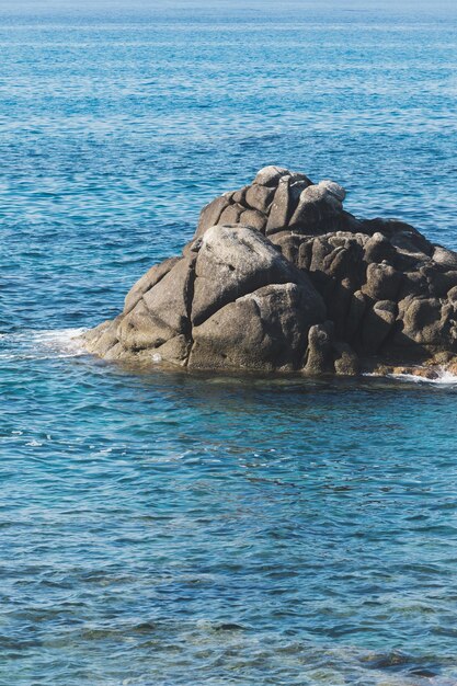 Litoral de praia rochosa selvagem e a onda do mar espirra na rocha na costa do mar mar calmo Ondas quebrando para as rochas na costa criando espuma branca do mar