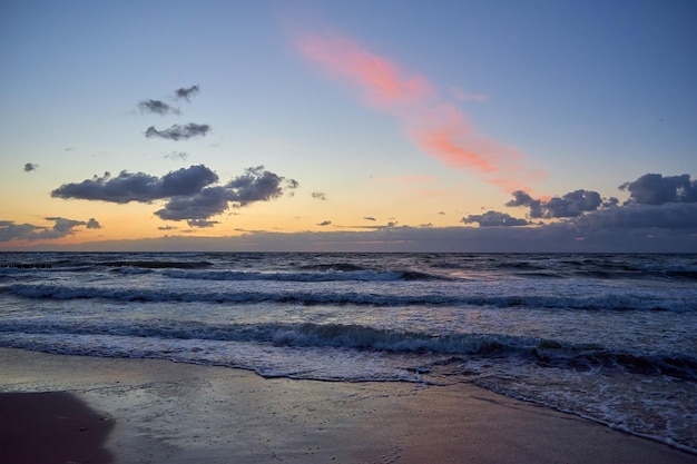 Litoral do mar com ondas do mar báltico contra o céu nublado dramático ao pôr do sol paisagem panorâmica da natureza