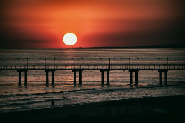 Litoral O sol se põe As cores do pôr do sol do céu Uma pessoa caminhando na praia Copiar espaço