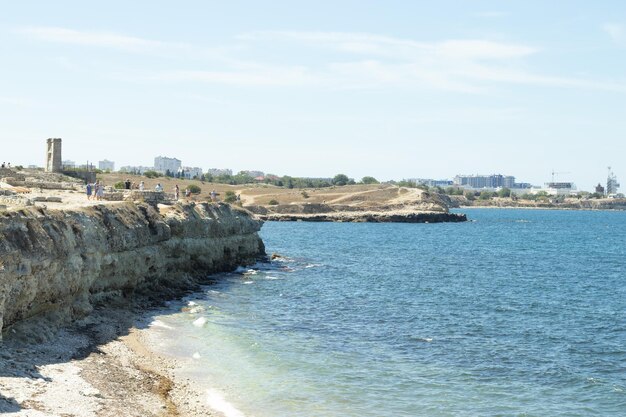 Litoral rochoso com turistas Cidade costeira no verão Céu azul e água