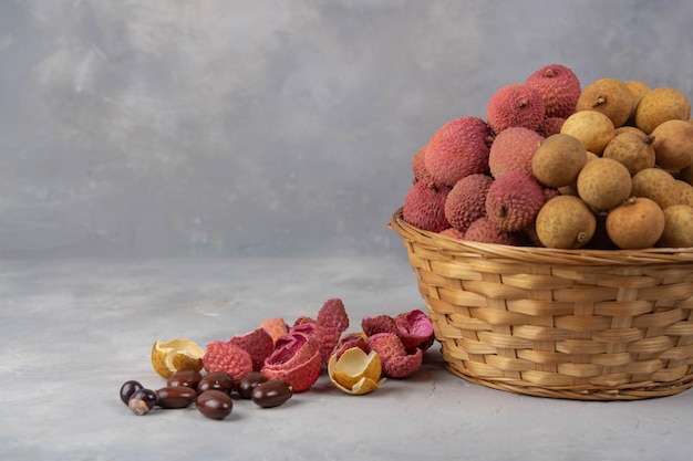 Litschi und Longan im Korb auf grauem Steinhintergrund Exotische Früchte auf dem Tablett zu Hause