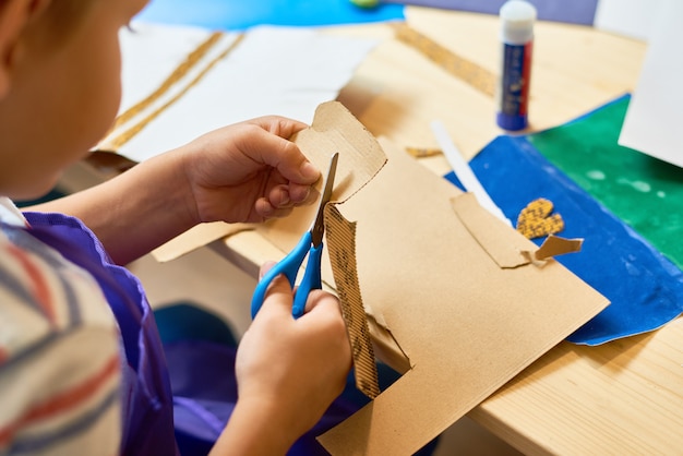 Little Boy cortando papel en clase artesanal